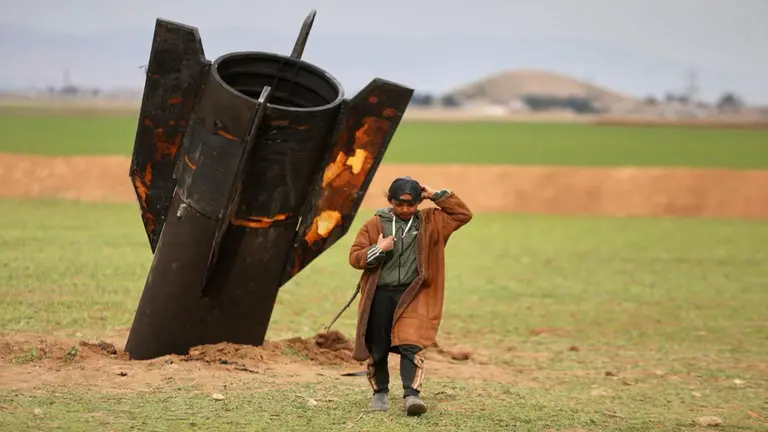 Inside the Iran Vs US-Israel War: 10 Defining Images of the Escalating Crisis A shepherd boy walks away from an unexploded Iranian projectile that landed in an open field in the outskirts of Qamishli, eastern Syria