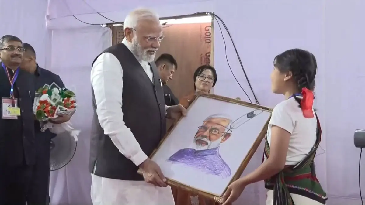 A girl presents Prime Minister Narendra Modi with his portrait in Churachandpur, Manipur, on Saturday.