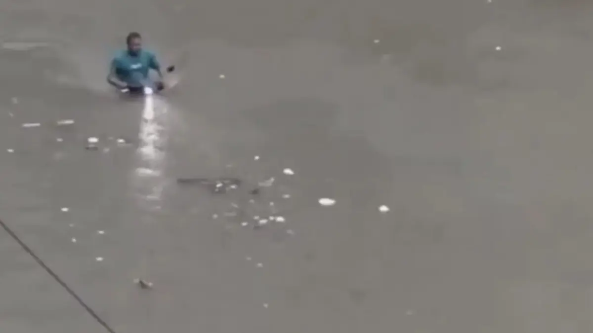 A man riding a two-wheeler through submerged streets