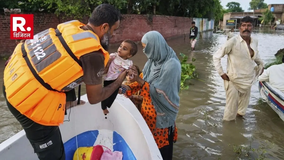 A rescue worker helps a family board in a boat to evacuate them from a flooded area in Dhoop Sarhi village in Kasur district, Pakistan