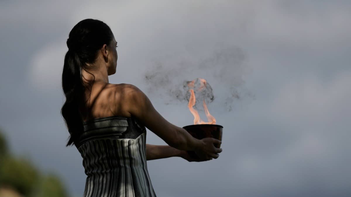Actress Mary Mina holds a pot with the flame during a rehearsal ahead of the flame lighting for the 2026 Winter Olympics