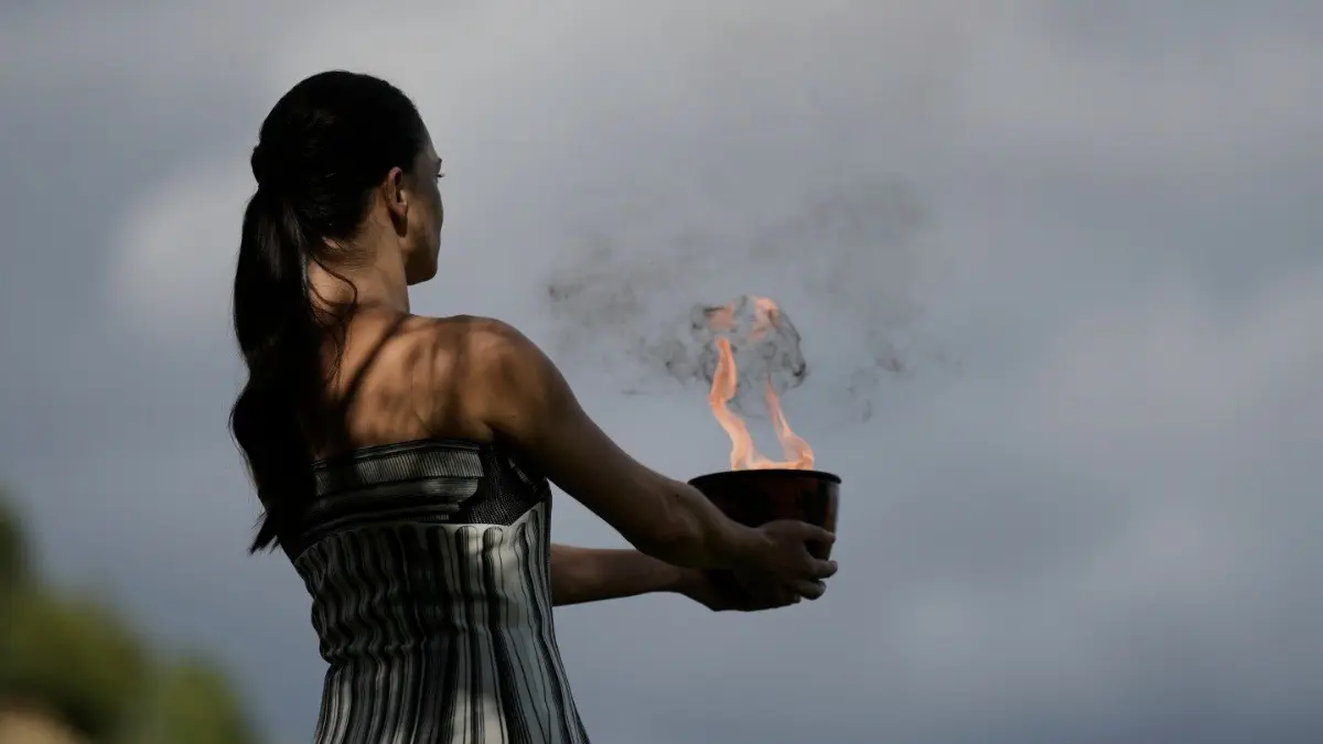 Actress Mary Mina holds a pot with the flame during a rehearsal ahead of the flame lighting for the 2026 Winter Olympics
