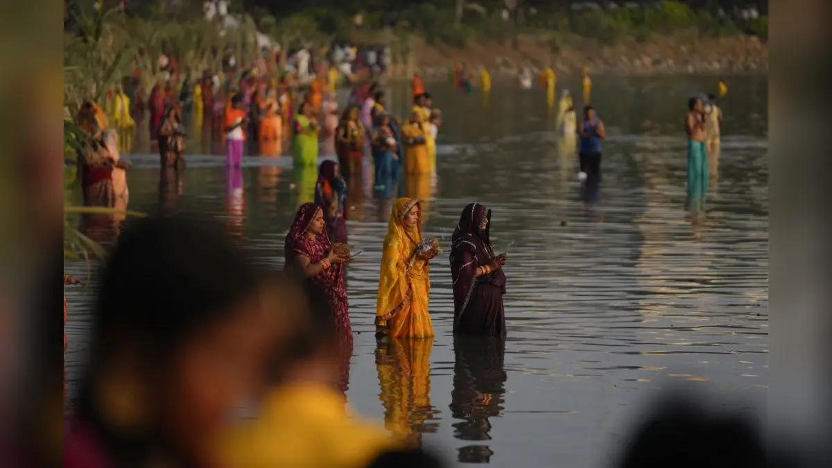 Devotees offering prayers during Chhath Puja as clouds gather over riverbank