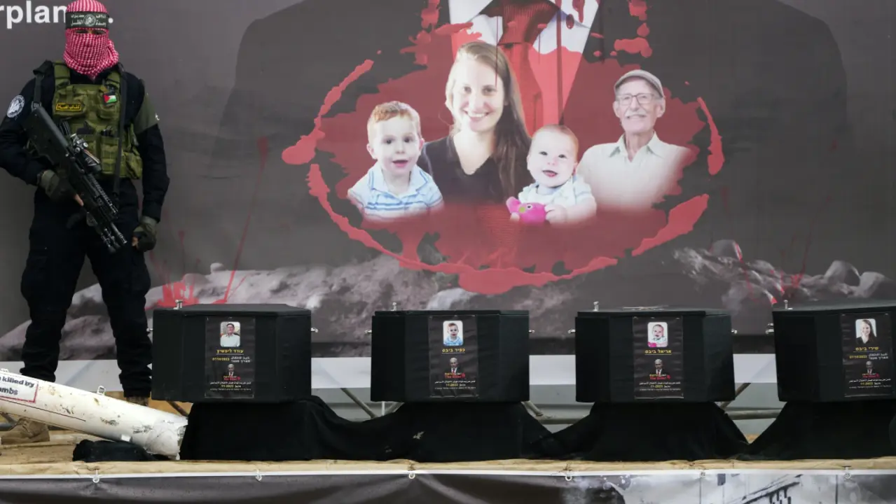 Hamas militant stands next to the coffins of four hostages in Khan Younis, Gaza