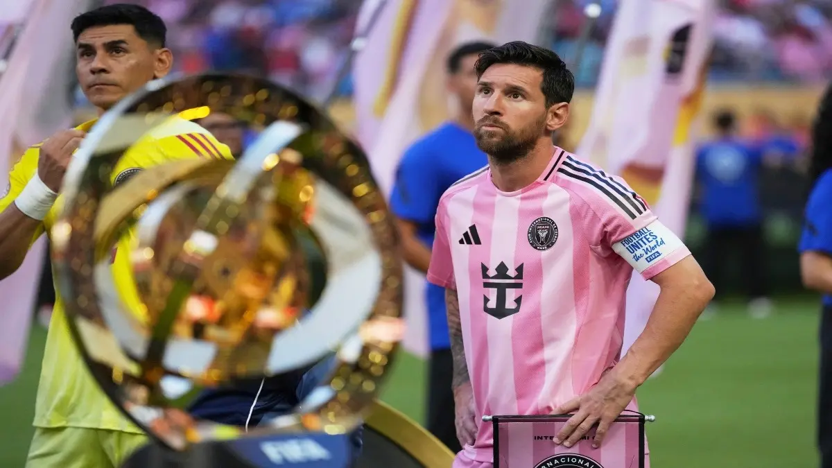 Lionel Messi stands next to the FIFA Club World Cup trophy