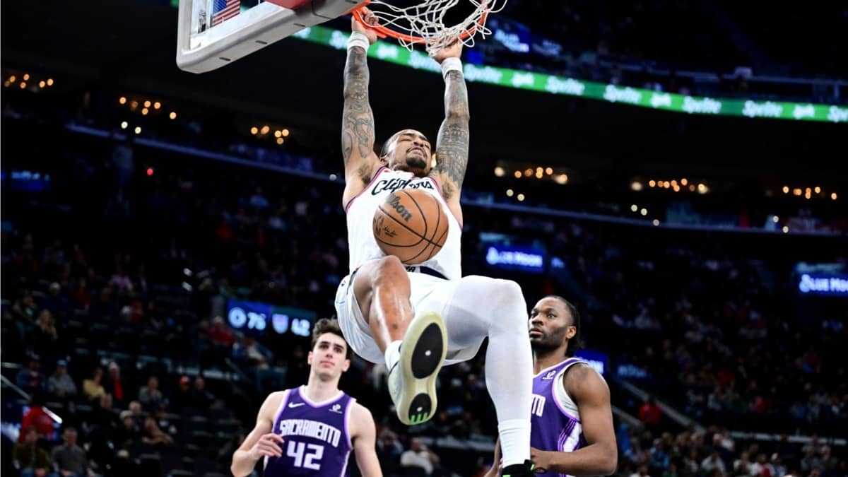 Los Angeles Clippers' John Collins dunks over Sacramento Kings center Maxime Raynaud, left, and forward Precious Achiuwa in the second half of an NBA fixture