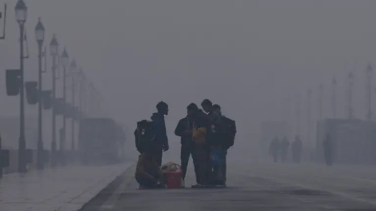People seen on Kartavya Path amid the dense fog on a cold winter morning, in New Delhi