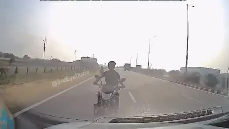 VIRAL: Biker Trying Risky Move Tragically Crushed By A Car On Guntur Highway | WATCH Video of a motorcycle and car accident on a highway in Andhra Pradesh went viral.