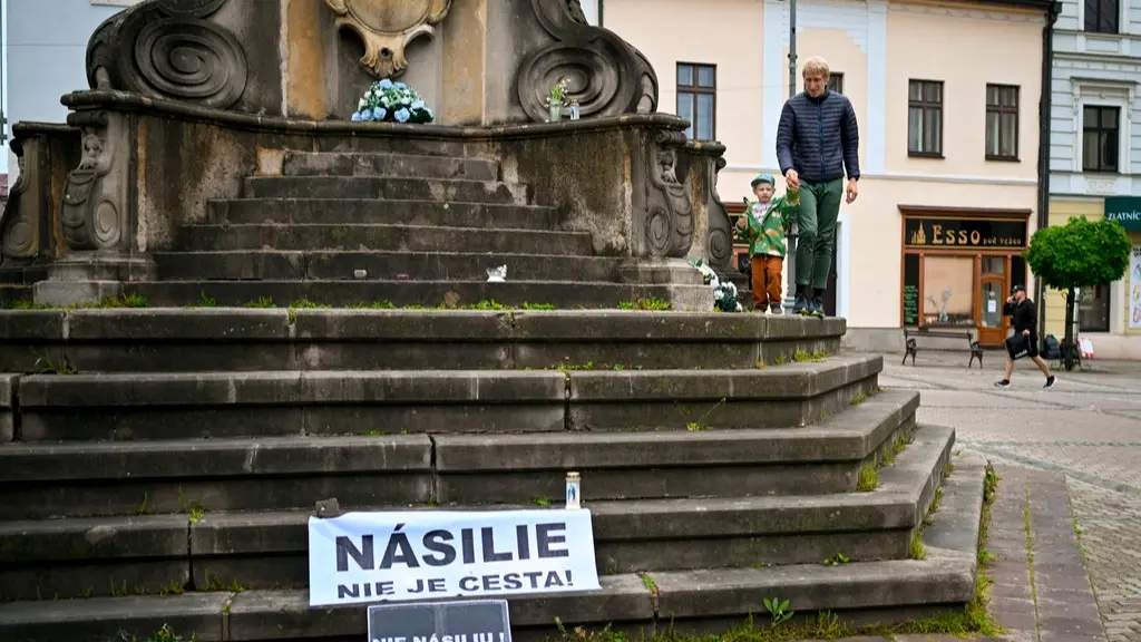 A man walks with a child next to a banner that reads "Violence is Not the Way" and " No Violence" in central Slovakia.