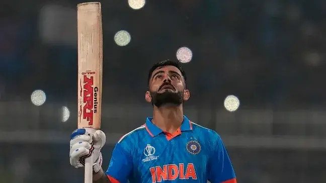 Indian batter Virat Kohli raises bat after scoring century