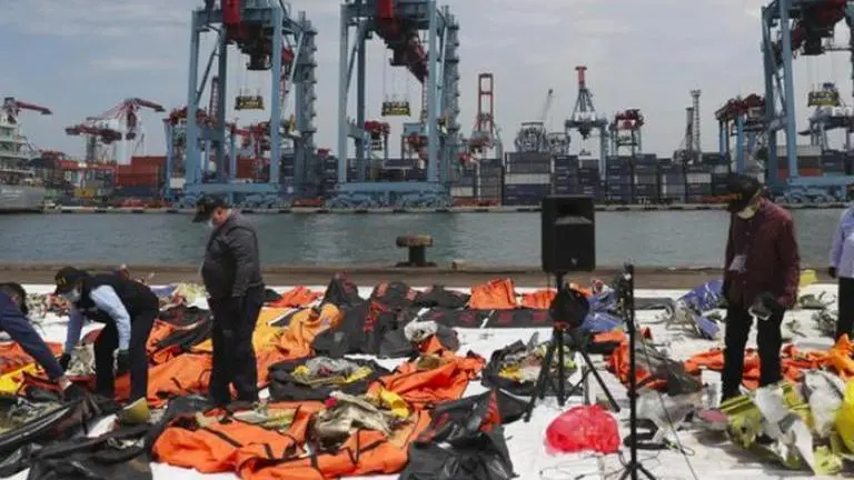 Relatives of plane's victims cast flowers into Indonesia sea