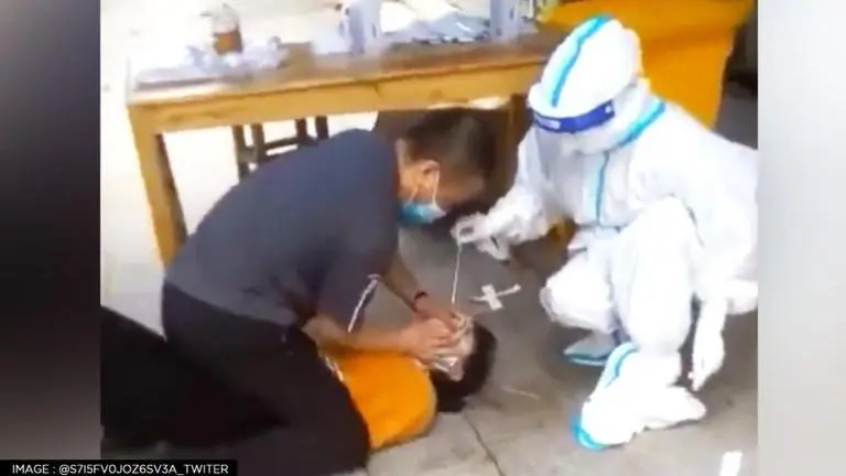 In China, woman forcefully pinned down as healthcare workers conduct COVID-19 test China