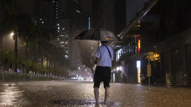 Hong Kong witnesses heaviest rainfall since 1884, flash floods left cities paralysed | A pedestrian waits for a bus on a flooded street following heavy rainstorms in Hong Kong