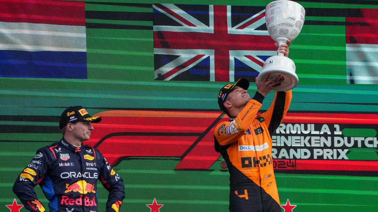 Lando Norris lifts the Dutch GP trophy as Max Verstappen watches on