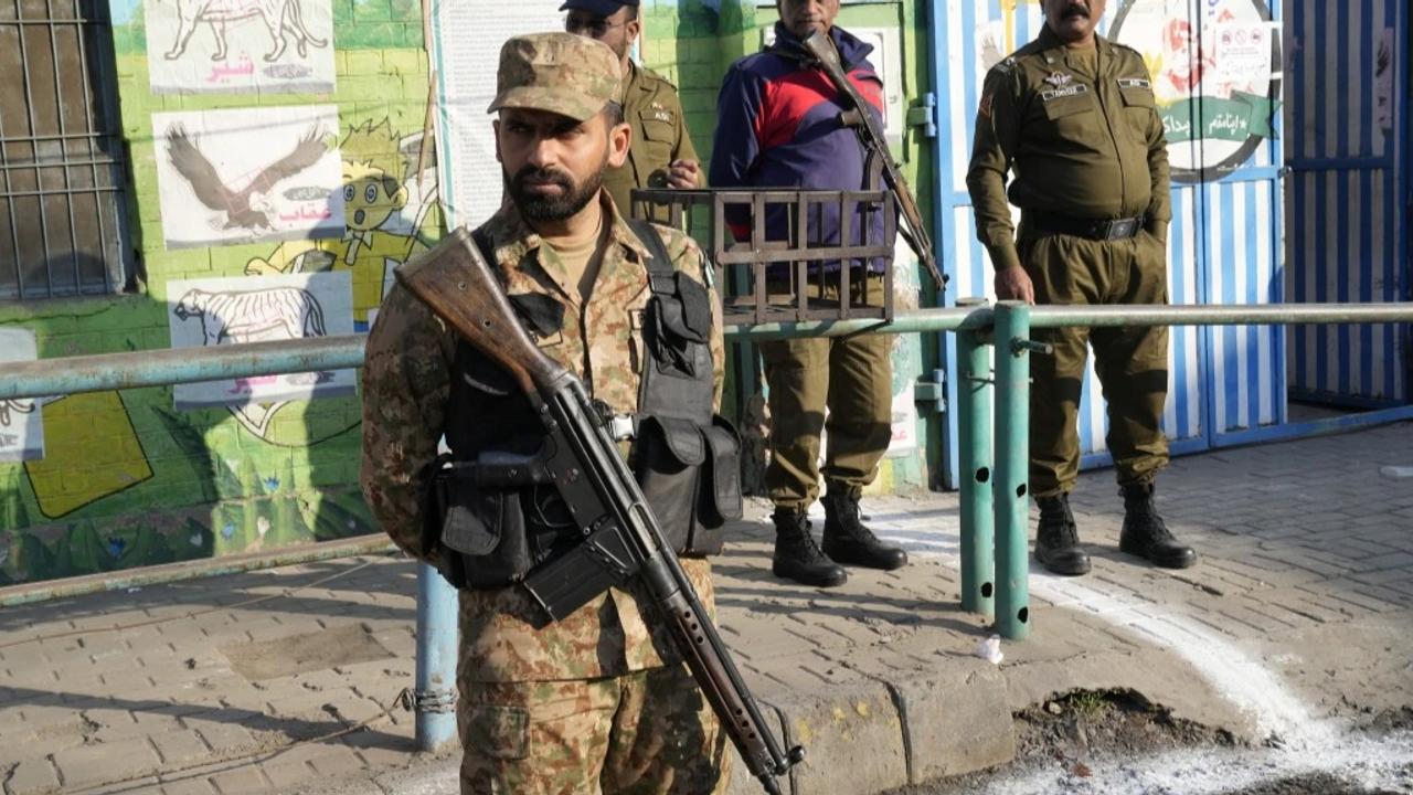 Pakistan's army soldier and police officers stand guard outside a polling station