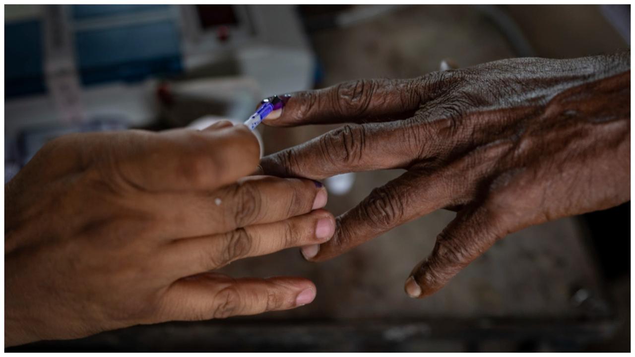 An official puts indelible ink mark on the index finger of a voter.