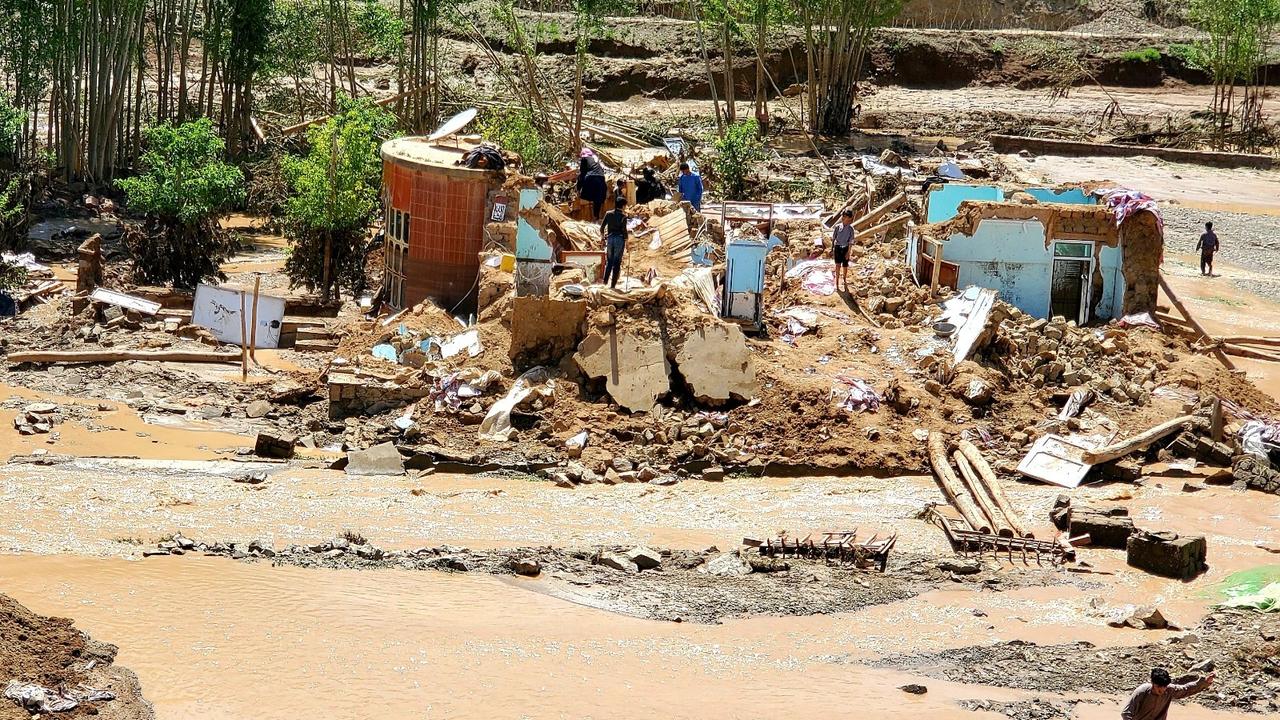 Afghan men collect their belongings from their damaged homes after heavy flooding in Ghor province in western Afghanistan, May 18, 2024.