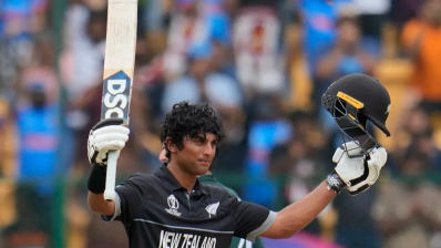 Rachin Ravindra raises his bat in celebration as he brings up his third century of the World Cup