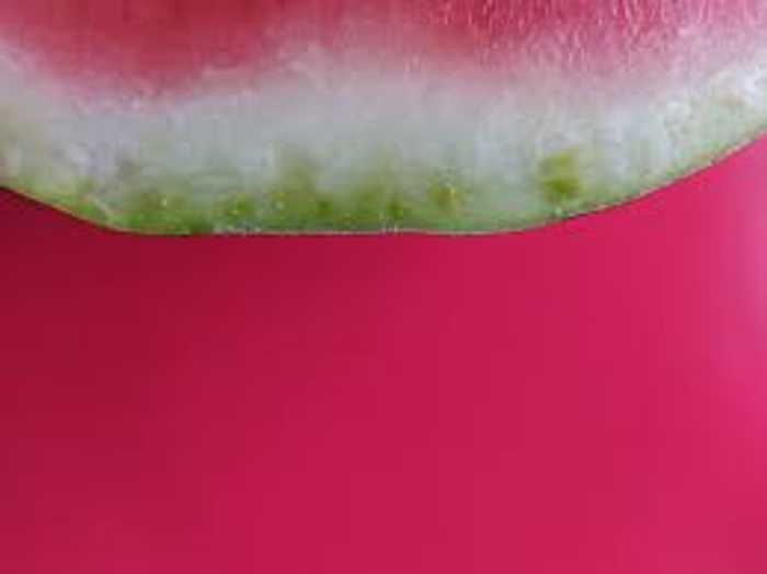 A slice of watermelon on a pink surface ...