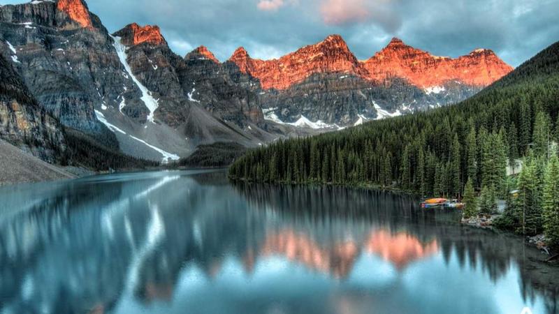 Nestled within the Canadian Rockies, Lake Louise presents a serene yet majestic view that changes with the seasons. In summer, the lake’s vibrant blue-green hue, fed by glacial meltwater, contrasts starkly with the lush greenery and wildflowers that surround it.