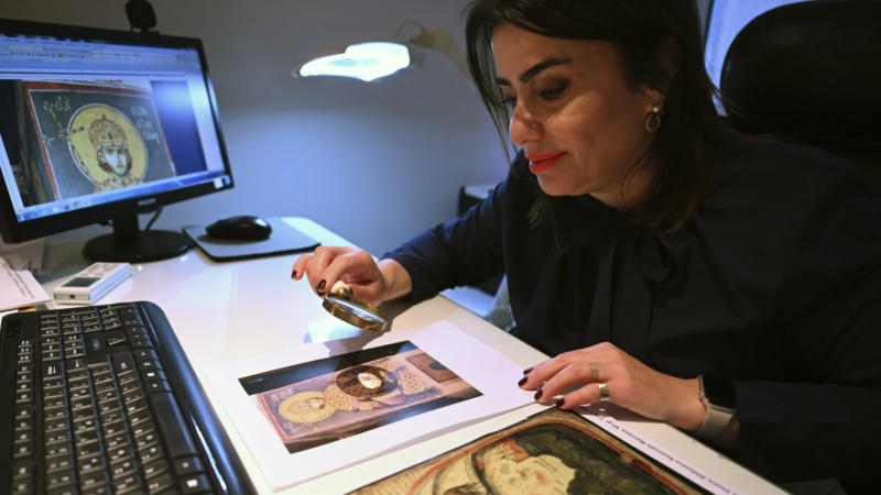 Christina Sotirakoglou a handwriting expert, observes Byzantine paintings based on photographs prints, at her office, in Thessaloniki, northern Greece, Saturday, November 30, 2024.