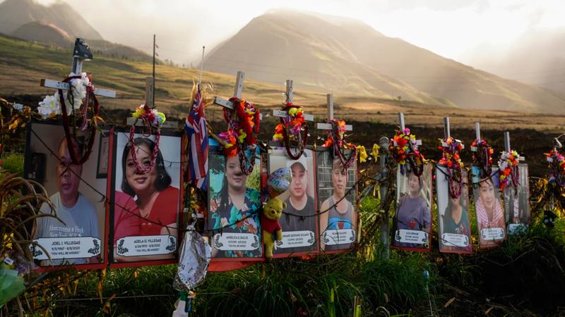 hotos of victims are displayed under white crosses at a memorial for victims of wildfire