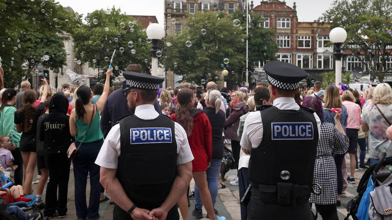 Police officers watch members of the public outside the Town Hall during a vigil to remember the victims of the stabbing attack last Monday in Southport, England