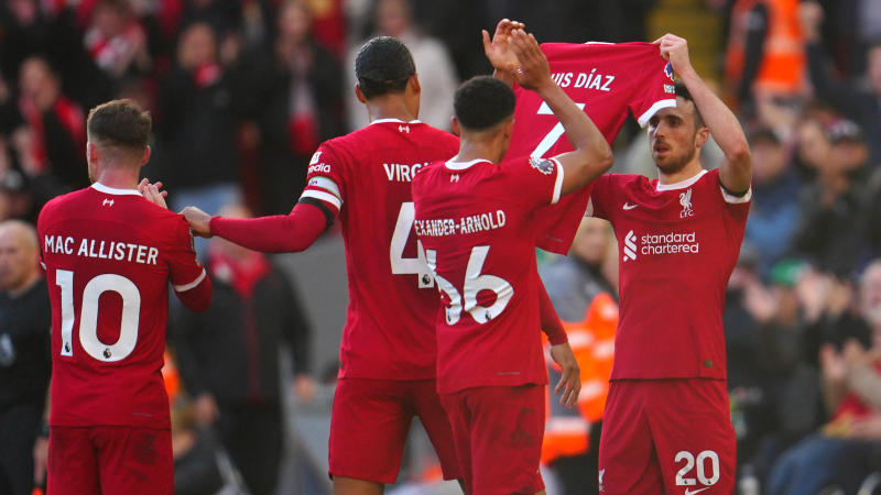 Liverpool players holding the jersey of Luis Diaz