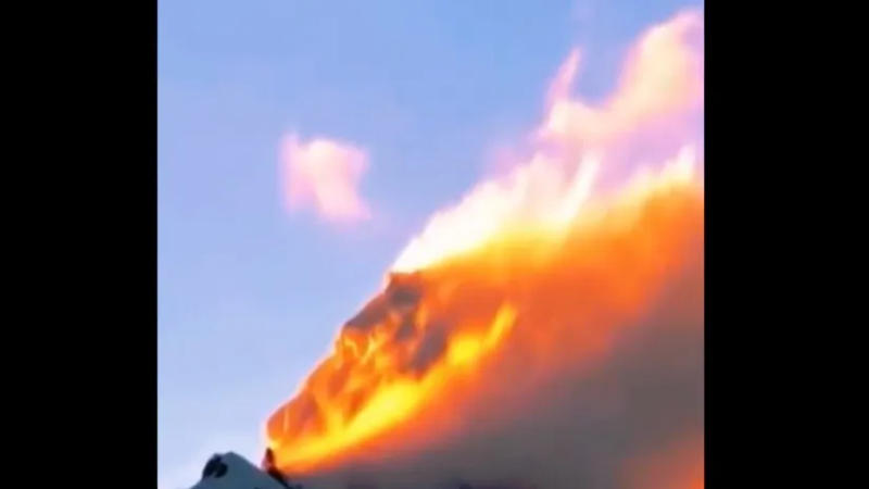 Sun setting over a snowy mountain creating an illusion of a wildfire