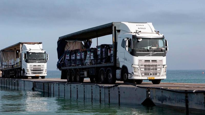 Trucks loaded with aid from the UAE and the US Agency for International Development cross the Trident Pier before entering the beach in Gaza