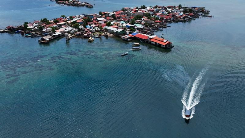 Civil protection officials move residents' belongings on a boat to the mainland from Gardi Sugdub Island, top, off Panama's Caribbean coast