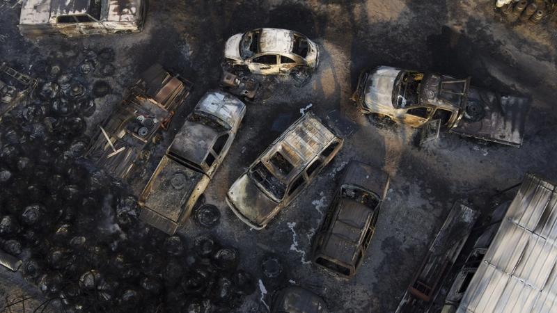 Charred vehicles sit at an auto body shop after the property was burned by the Smokehouse Creek Fire