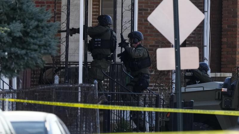 Law enforcement officers enter an empty apartment in Trenton