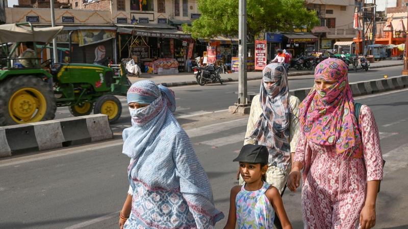 People cover their head and face for protection from the scorching heat on a hot summer day, in Ayodhy