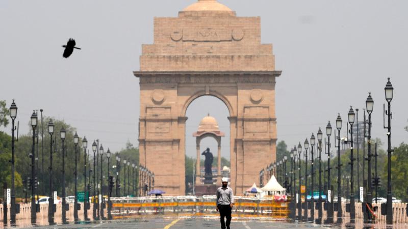 A man walks past the India Gate monument on a hot summer day in New Delhi,