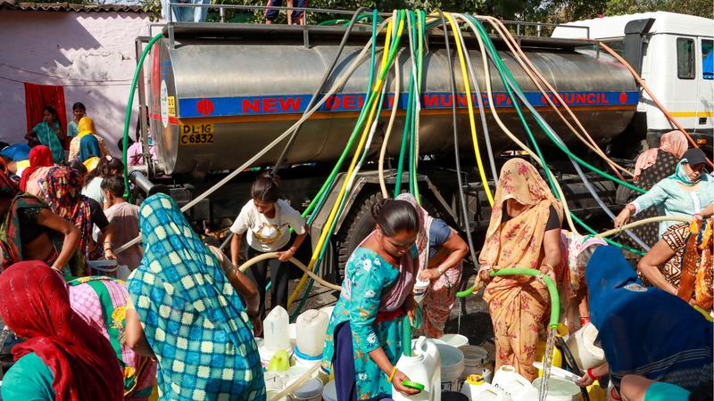 People collect drinking water from a tanker on a hot summer day, at Vivekanand camp, in New Delhi