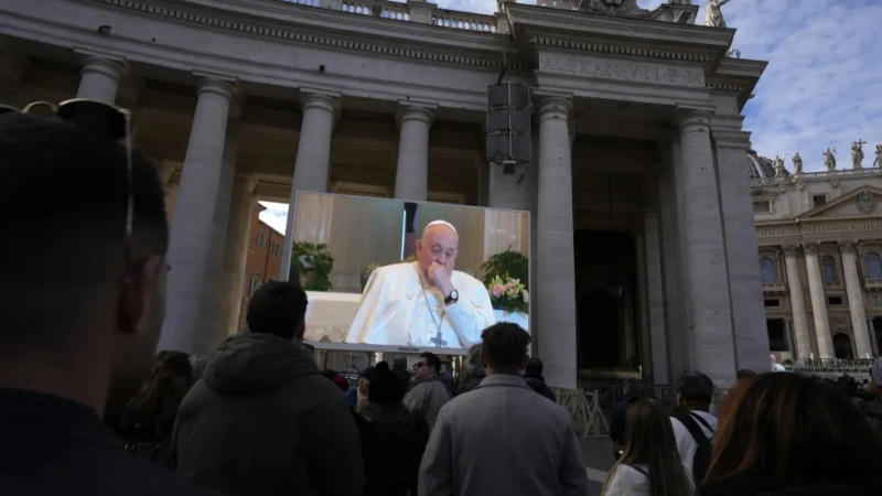 A giant screen broadcasts Pope Francis coughing during the Angelus noon prayer.