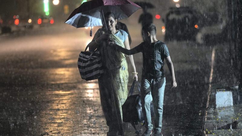 A pedestrian uses an umbrella to shield herself during rains, outside CSMT in Mumbai. 