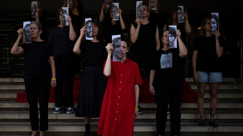 Relatives and supporters of Israeli hostages held by Hamas in Gaza hold photos of their loved ones during a performance calling for their return in Tel Aviv, May 23, 2024. 