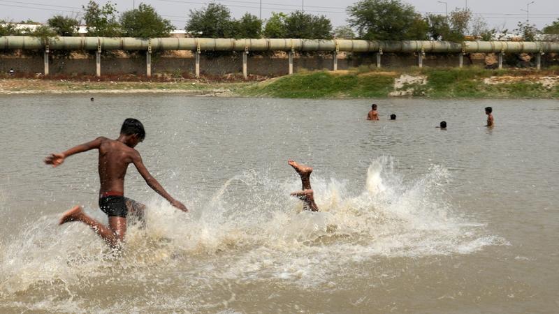 Children cool themselves in a lake as the temperature rises in New Delhi, May 27, 2024. 