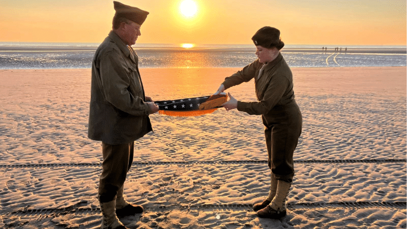 Christophe Receveur and his daughter Julie, of France, unfold an American flag he bought six month ago in Gettysburg, Penn., to mark D-Day, June 6, 2024 on Utah Beach, Normandy