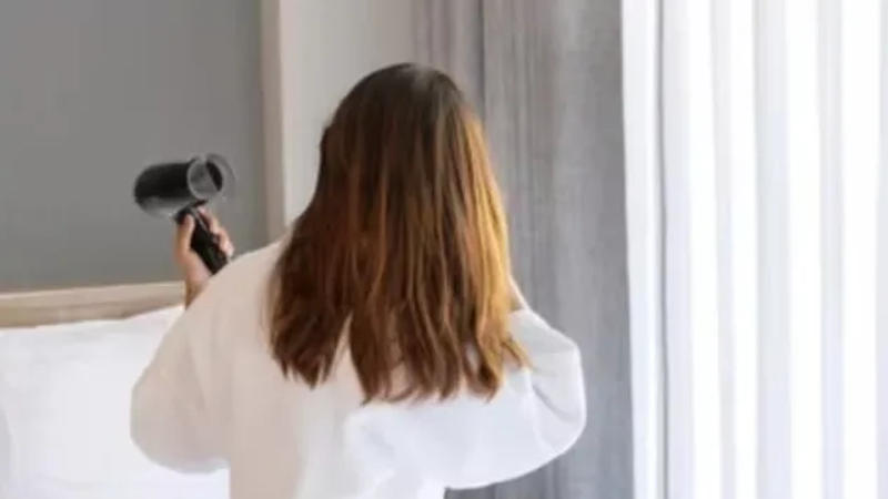  Woman using hairdyer at Hotel 